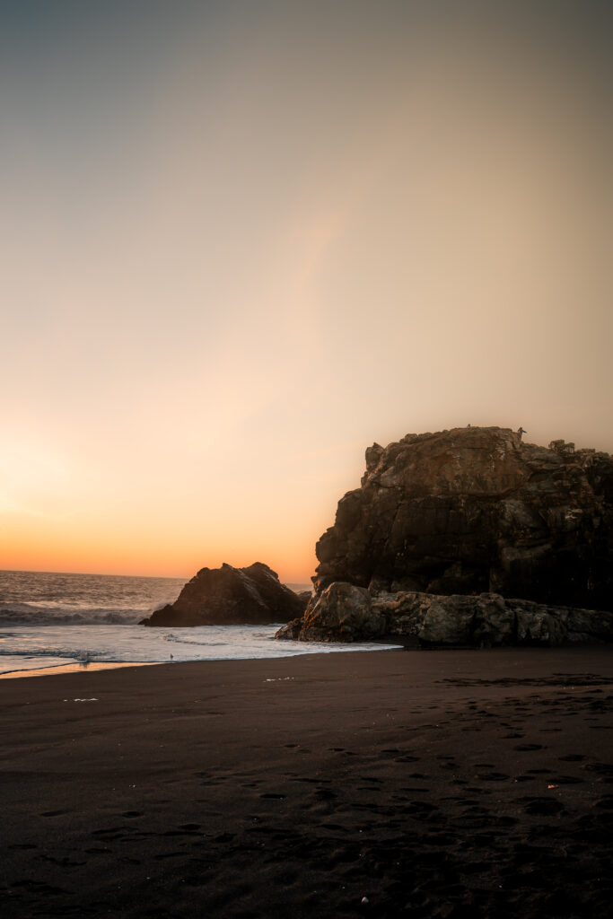 A rocky beach at sunset with colorful sky