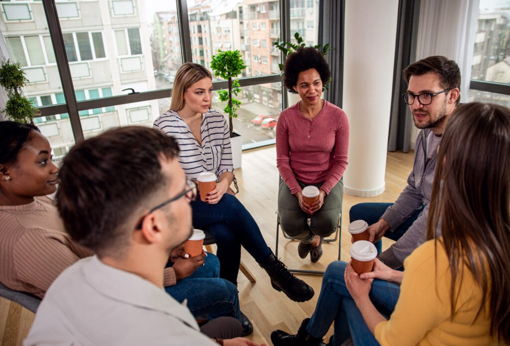 Diverse group of people sitting in circle in group therapy session.